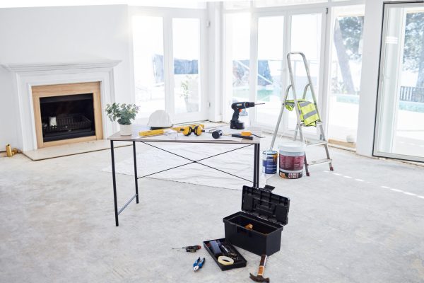 Shot of building plans and equipment on a table in an empty living room during the day.